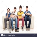 sad-group-of-young-men-looking-at-television-sitting-on-a-couch-C57HA1.jpg